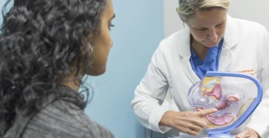 Profesional de salud mostrando modelo anatómico del aparato reproductor femenino a paciente durante consulta ginecológica