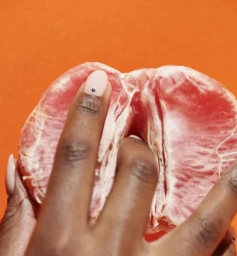 Mano abriendo un pomelo, representación simbólica de la vulva y el placer femenino.